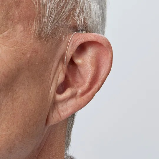 Homem usando aparelho auditivo Bernafon Encanta miniRITE atrás da orelha